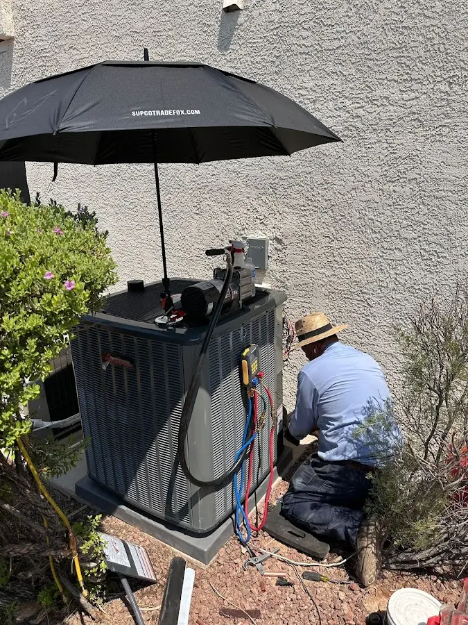 HVAC technician performing outdoor AC maintenance in Gilbert